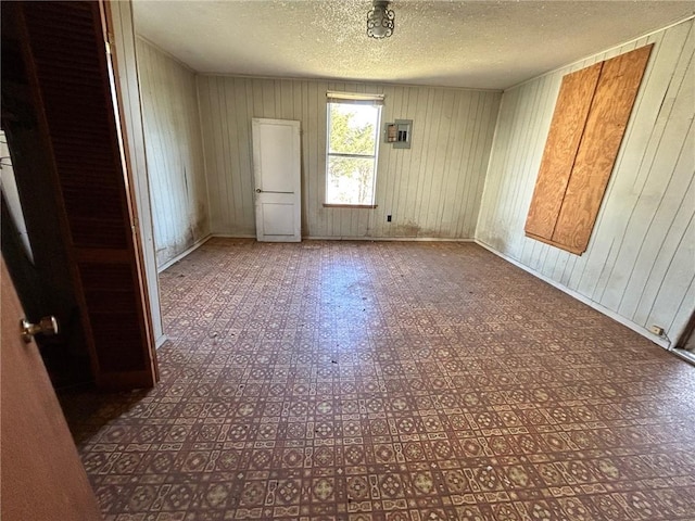 empty room featuring wooden walls and a textured ceiling