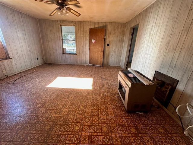 empty room featuring heating unit, ceiling fan, and wooden walls