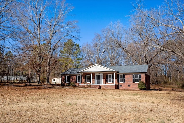 ranch-style home featuring covered porch and a front yard