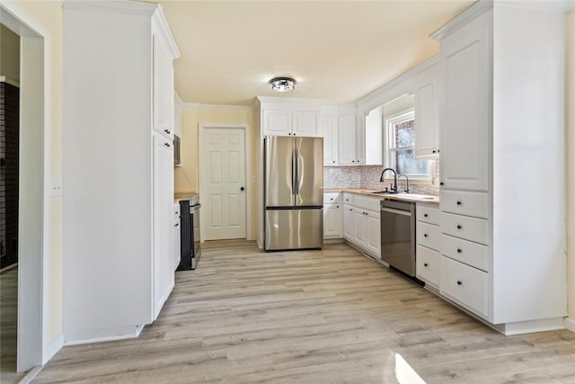 kitchen featuring appliances with stainless steel finishes, white cabinetry, sink, backsplash, and light wood-type flooring