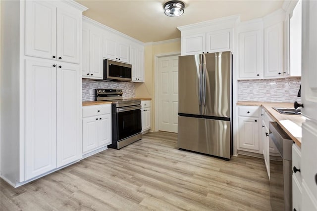 kitchen with light hardwood / wood-style floors, appliances with stainless steel finishes, tasteful backsplash, white cabinetry, and wood counters