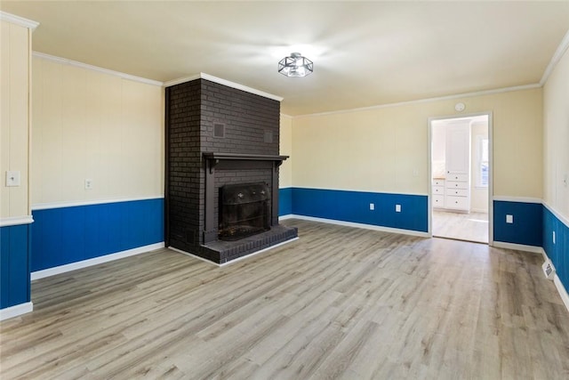 unfurnished living room with light wood-type flooring, crown molding, and a fireplace