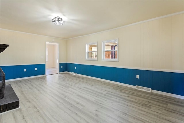 interior space with light hardwood / wood-style floors, a wood stove, and ornamental molding