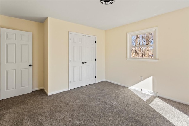 unfurnished bedroom featuring a closet and dark carpet