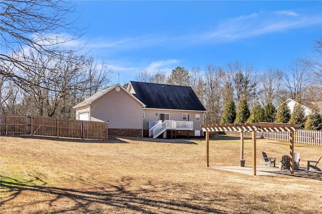 back of property with a patio, a lawn, a wooden deck, and a fire pit