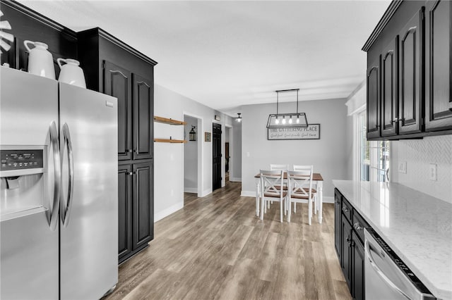 kitchen with hanging light fixtures, appliances with stainless steel finishes, light hardwood / wood-style flooring, and tasteful backsplash