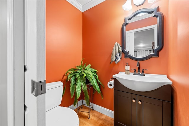 bathroom featuring ornamental molding, wood-type flooring, vanity, and toilet