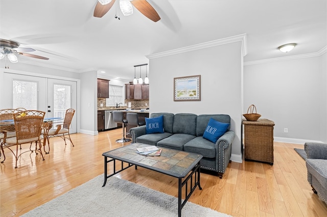 living room with ornamental molding, french doors, ceiling fan, and light wood-type flooring