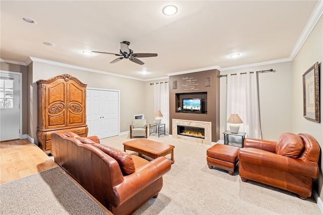 living room featuring ceiling fan, ornamental molding, a premium fireplace, and light hardwood / wood-style floors