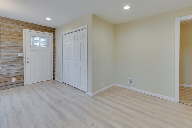 foyer with wooden walls and light hardwood / wood-style flooring