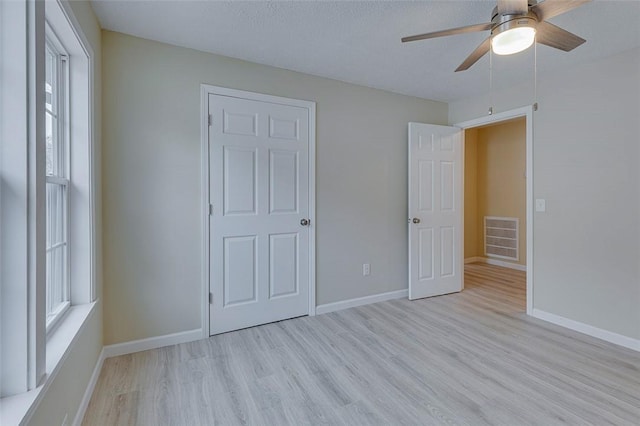 unfurnished bedroom with ceiling fan, a textured ceiling, and light hardwood / wood-style flooring