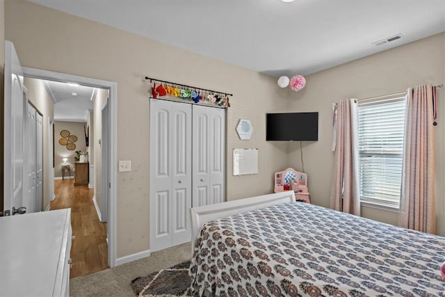 bedroom with light hardwood / wood-style floors, multiple windows, and a closet