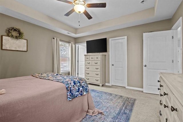 bedroom with ceiling fan, a raised ceiling, and light carpet