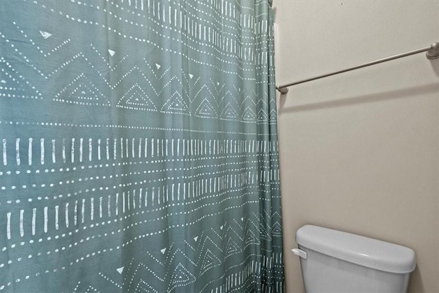 bathroom featuring toilet and a shower with curtain