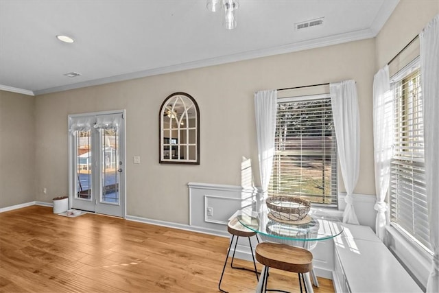 dining area with a wealth of natural light, crown molding, and light hardwood / wood-style floors