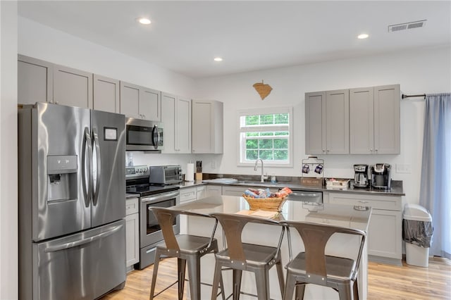 kitchen with sink, dark stone counters, a center island, a breakfast bar area, and stainless steel appliances