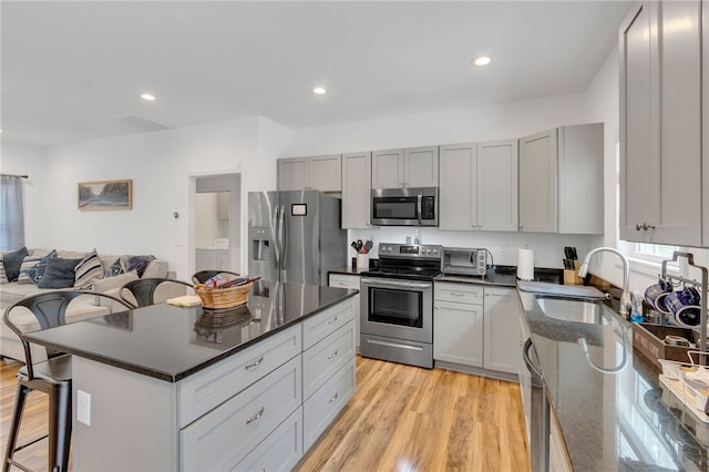 kitchen featuring appliances with stainless steel finishes, sink, a kitchen island, light hardwood / wood-style floors, and a breakfast bar area