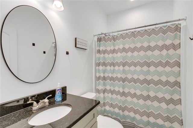 bathroom featuring toilet, vanity, and a shower with curtain