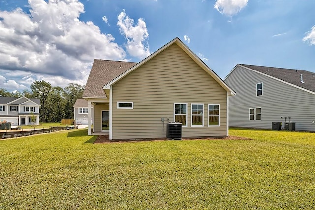 rear view of property featuring a yard and central AC