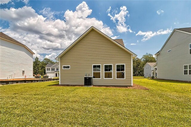 rear view of house featuring a lawn and cooling unit