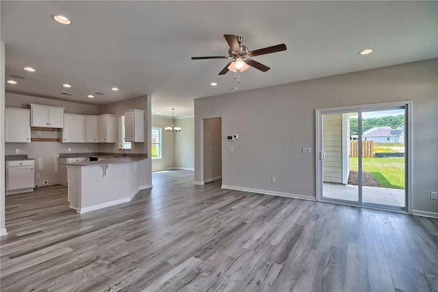 kitchen with a kitchen breakfast bar, white cabinetry, light hardwood / wood-style flooring, and kitchen peninsula