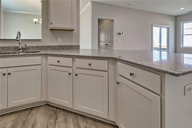 kitchen with sink, light stone counters, and white cabinets