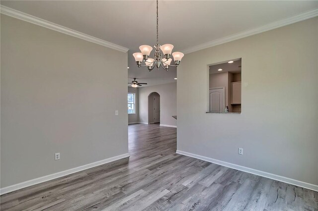 empty room with ceiling fan with notable chandelier, crown molding, and wood-type flooring