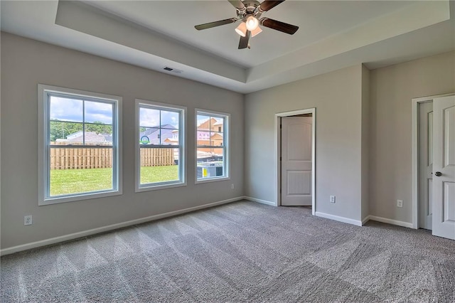 unfurnished bedroom featuring carpet, ceiling fan, and a raised ceiling