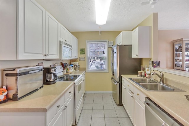 kitchen featuring appliances with stainless steel finishes, sink, white cabinetry, light tile patterned floors, and a textured ceiling