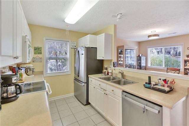 kitchen featuring sink, white cabinets, light tile patterned floors, a textured ceiling, and stainless steel appliances