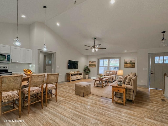 living room with light wood-type flooring, ceiling fan, and high vaulted ceiling