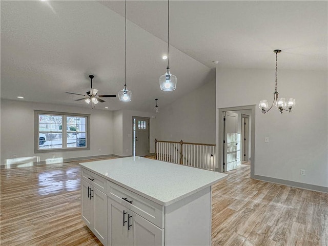 kitchen featuring light hardwood / wood-style flooring, vaulted ceiling, hanging light fixtures, white cabinets, and a center island