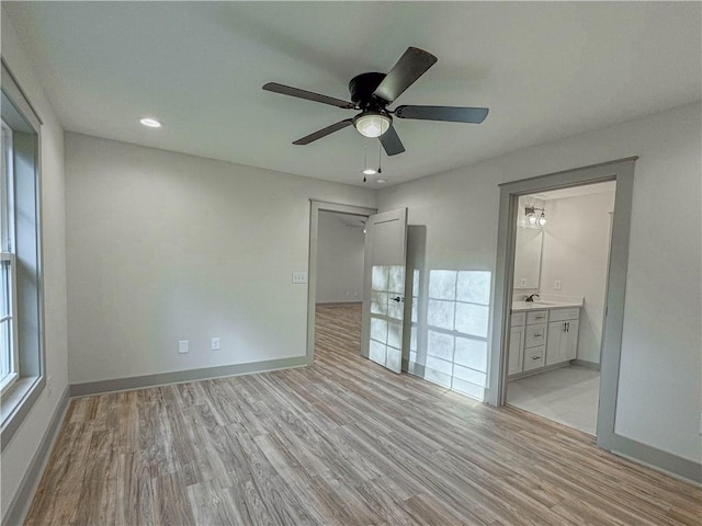 unfurnished bedroom with ceiling fan, light hardwood / wood-style floors, connected bathroom, and sink