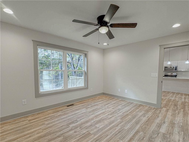 empty room with ceiling fan and light hardwood / wood-style flooring