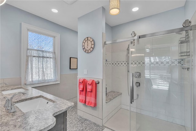 bathroom featuring a shower with shower door, tile walls, vanity, and a wealth of natural light