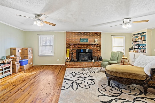 living room featuring ceiling fan, ornamental molding, a textured ceiling, and wood-type flooring