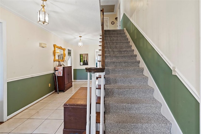 stairway with tile patterned floors and crown molding