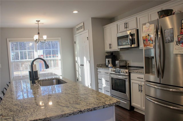 kitchen featuring pendant lighting, sink, white cabinets, and appliances with stainless steel finishes