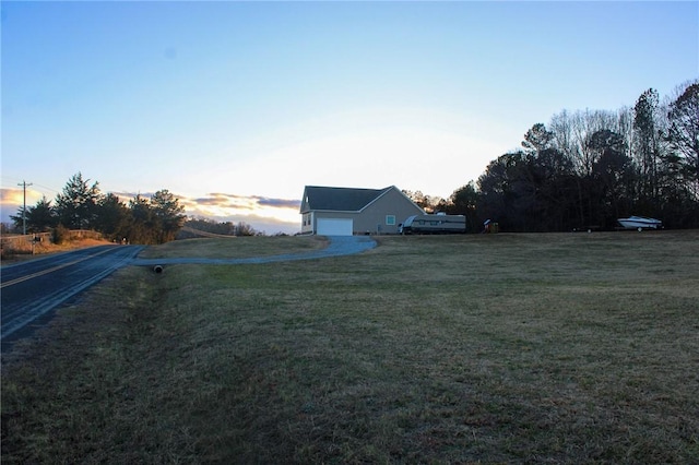 yard at dusk featuring a garage