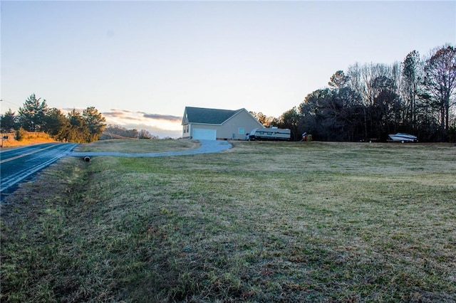 yard at dusk featuring a garage