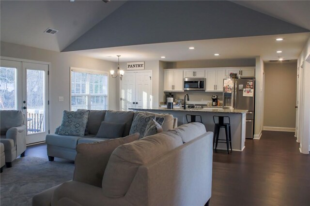 living room featuring plenty of natural light, a chandelier, dark hardwood / wood-style floors, and lofted ceiling