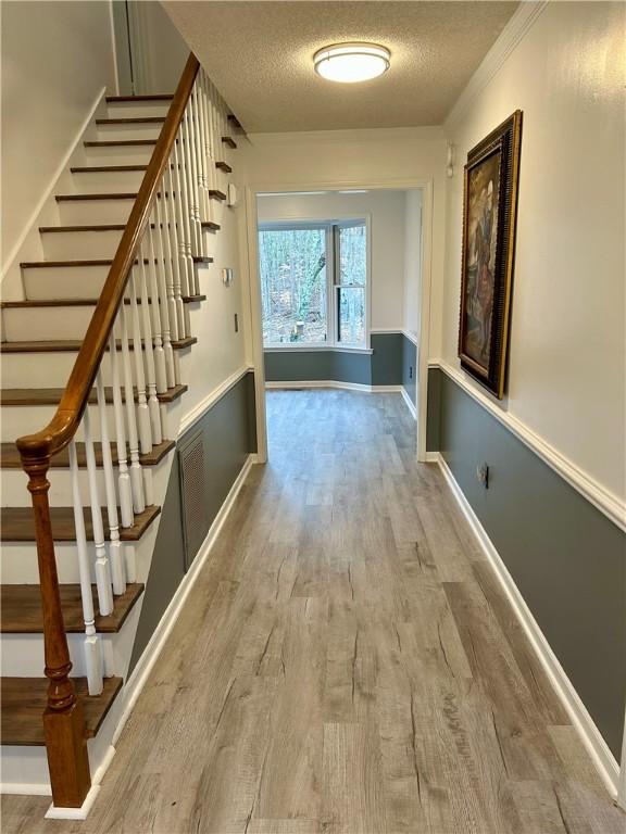 corridor with a textured ceiling, baseboards, and wood finished floors