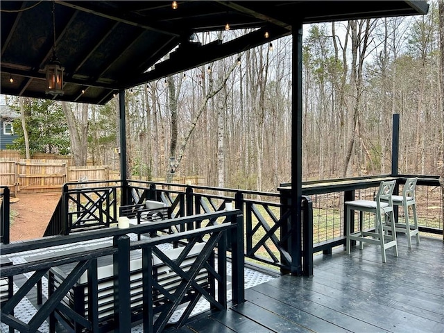 wooden terrace featuring fence and a view of trees