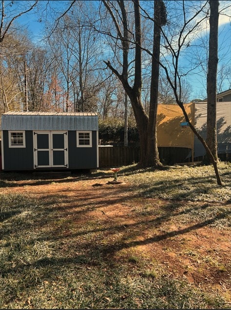 view of yard featuring a storage shed, fence, and an outbuilding