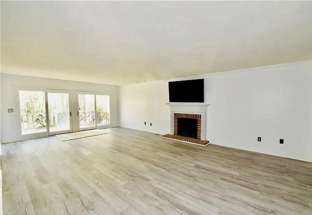 unfurnished living room with a brick fireplace and wood finished floors