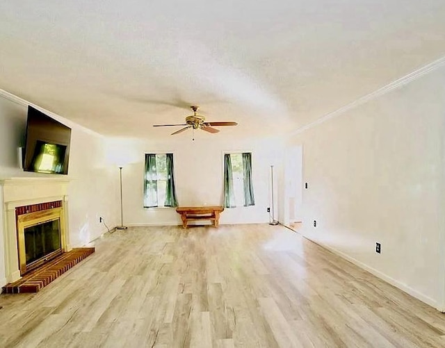 unfurnished living room featuring ornamental molding, a brick fireplace, light wood-style flooring, and a ceiling fan