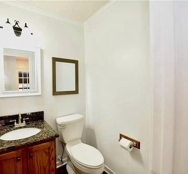 bathroom with ornamental molding, vanity, and toilet