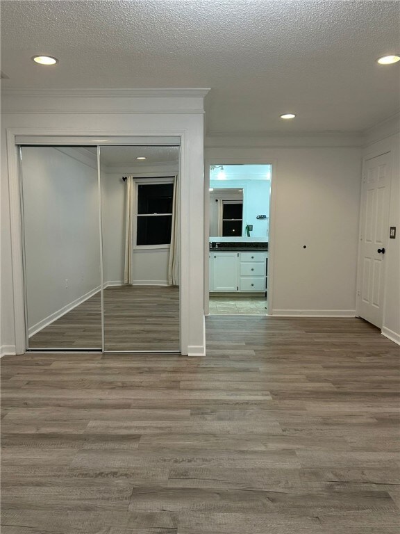 interior space with ornamental molding, recessed lighting, a textured ceiling, and wood finished floors