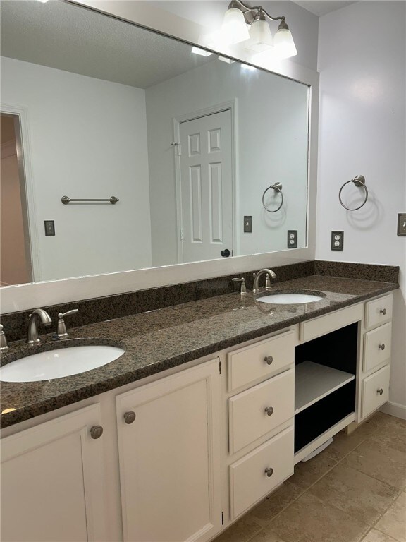 full bathroom with tile patterned floors, a sink, and double vanity