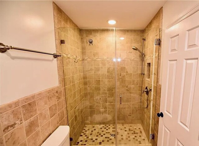 full bath featuring a shower stall and toilet